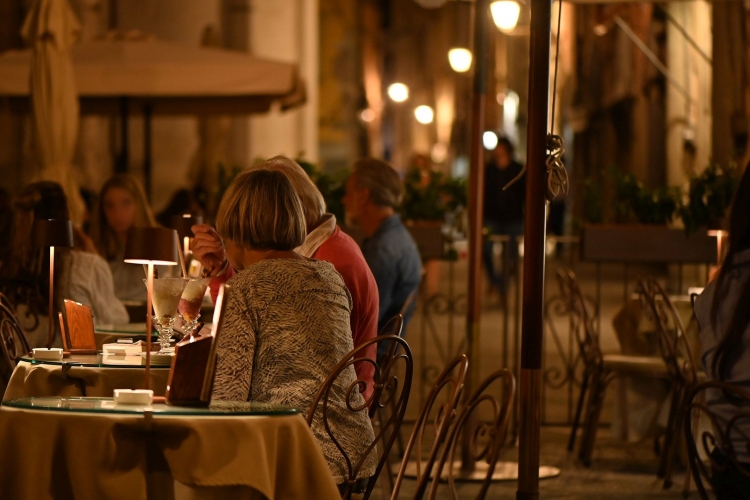 Deux femmes sont assises à la table d'un bar dans le centre historique de Lucques, le soir.